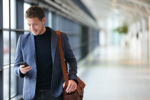 Man on smart phone - young business man in airport. Casual urban